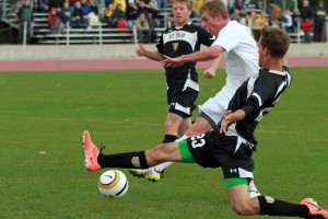 Ryan Tollefsrud tucks a shot under the leg of a sliding St. Olaf defender for the opening goal of the match. 